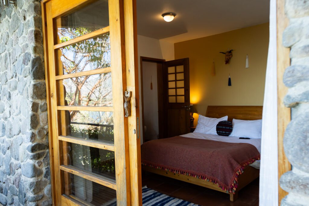 Villa Bambu bedroom with stone walls, wooden door, and cozy bed.
