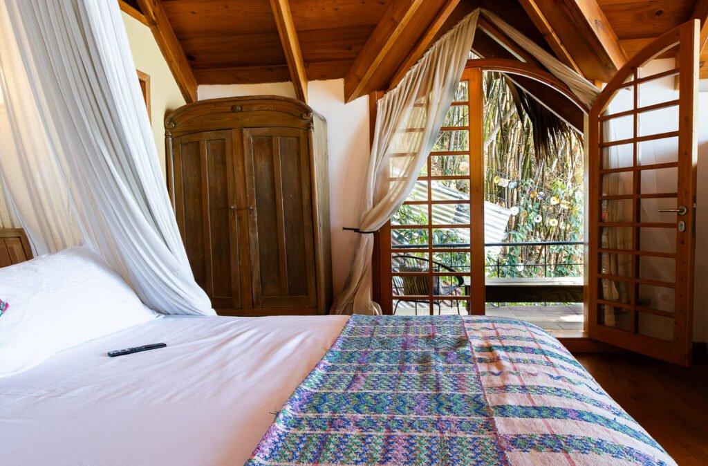 Bedroom at Villa Bambu with open doors to a balcony and lush greenery outside.