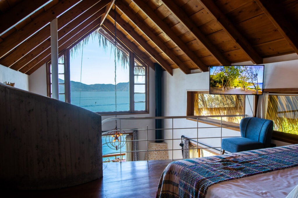 Villa Bambu interior with lake view from a loft bedroom under a vaulted wooden ceiling.