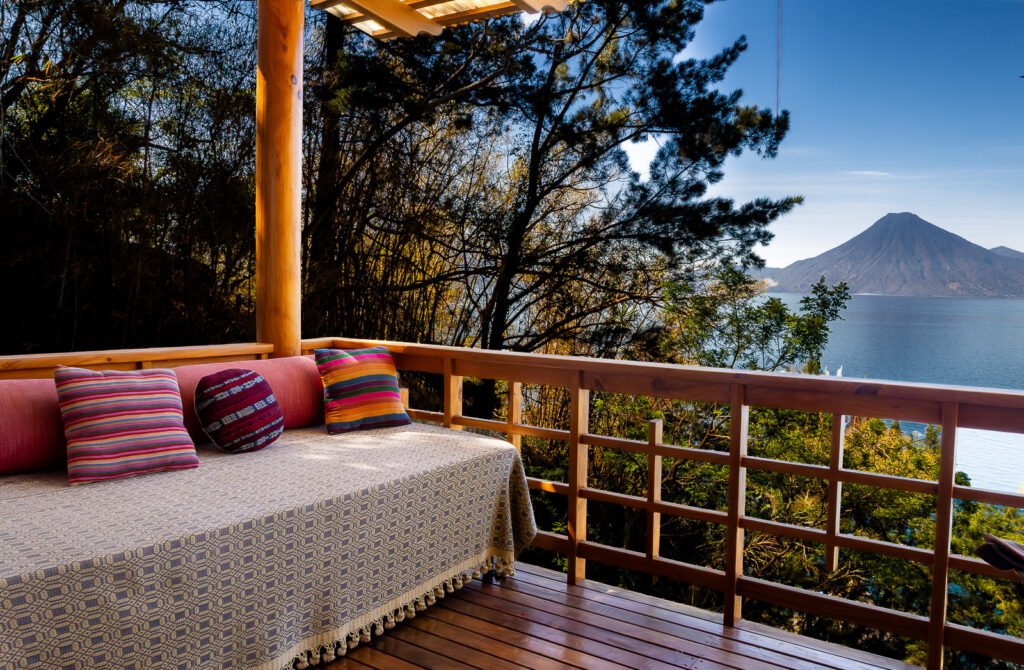 Villa Bambu balcony view of Lake Atitlan and volcano with colorful pillows on daybed.