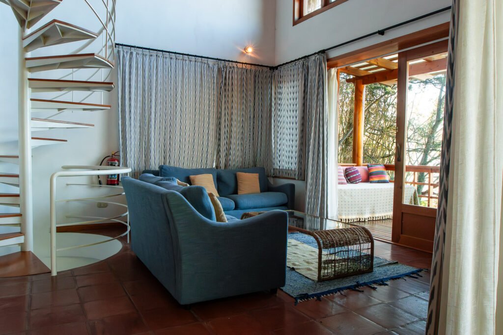 Villa Bambu living room with blue sofa, spiral staircase, and balcony view.