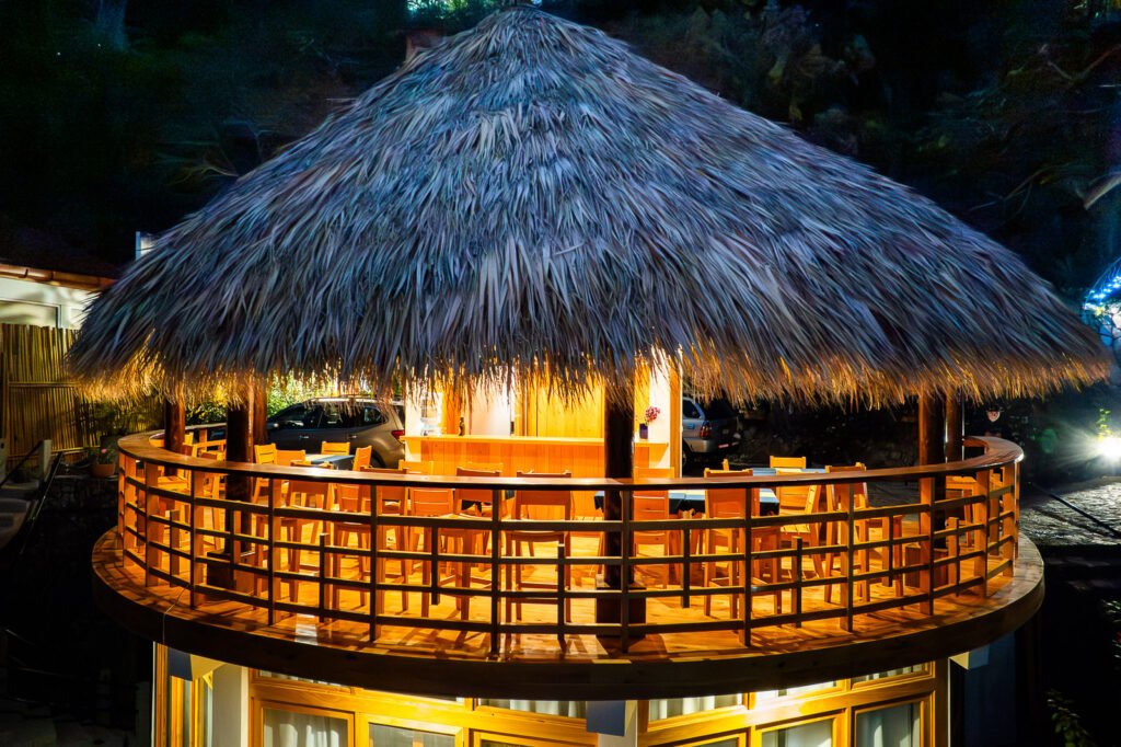 B'alam Ya Cafe outdoor seating area with a thatched roof at night.
