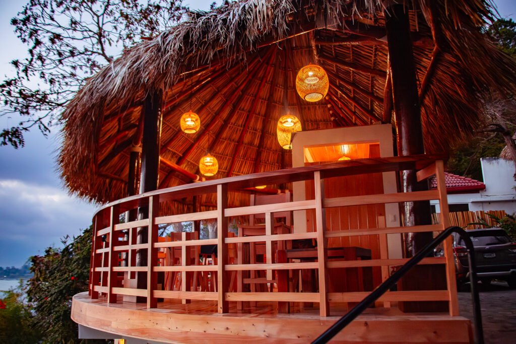 B'alam Ya Cafe's inviting thatched-roof structure with warm lighting and wooden railing.