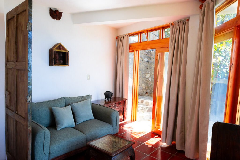 Villa Gio living room with sofa, terracotta tile floor, and open doors to the outside.