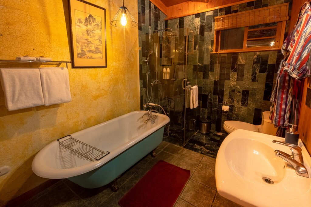 Villa Jade bathroom with clawfoot tub, green marble shower, and sink.
