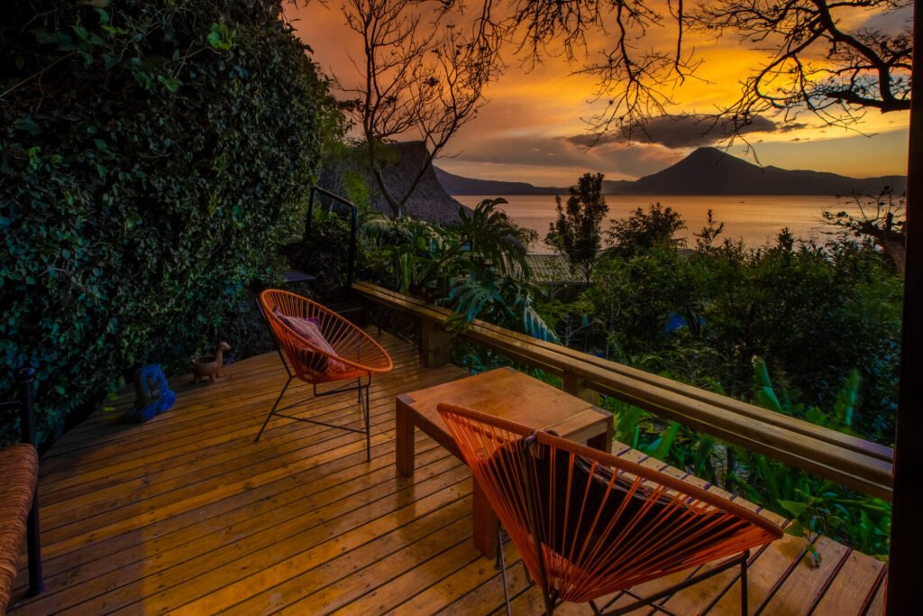 Villa Jade balcony with orange chairs overlooking a sunset over a lake and volcano.