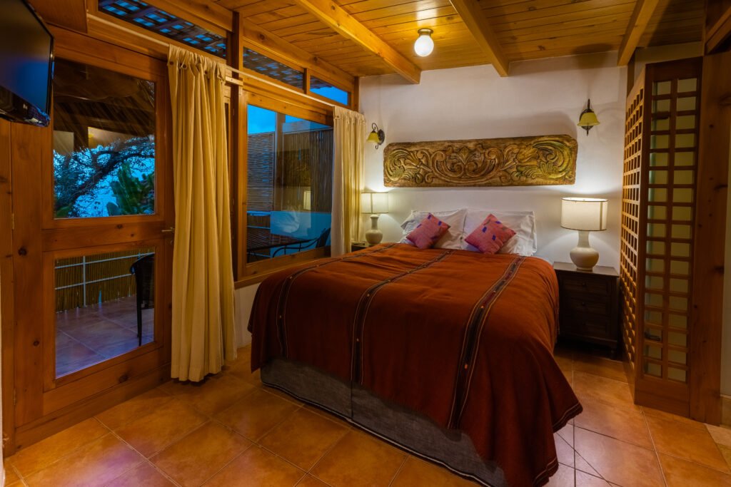 Villa Loft bedroom with king-size bed, wooden beams, and patio view