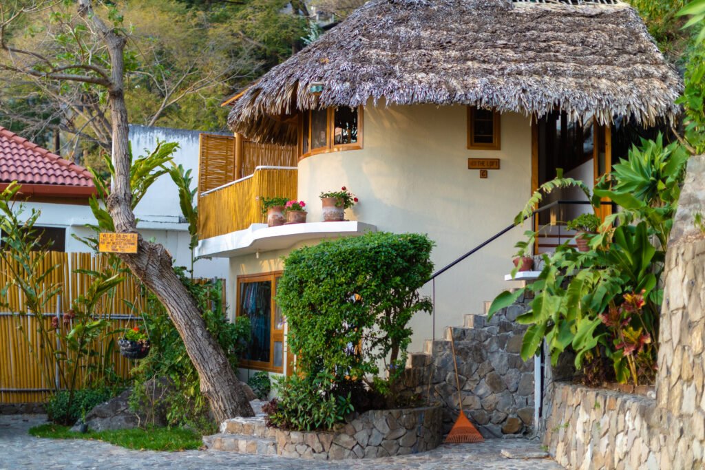 Villa Loft: Charming thatched-roof bungalow with stone stairs and lush greenery.