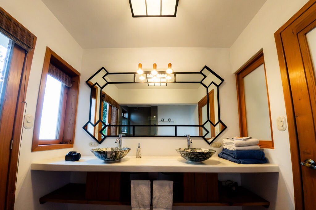 Villa Mirador bathroom with double sinks, decorative mirror, and wooden accents.