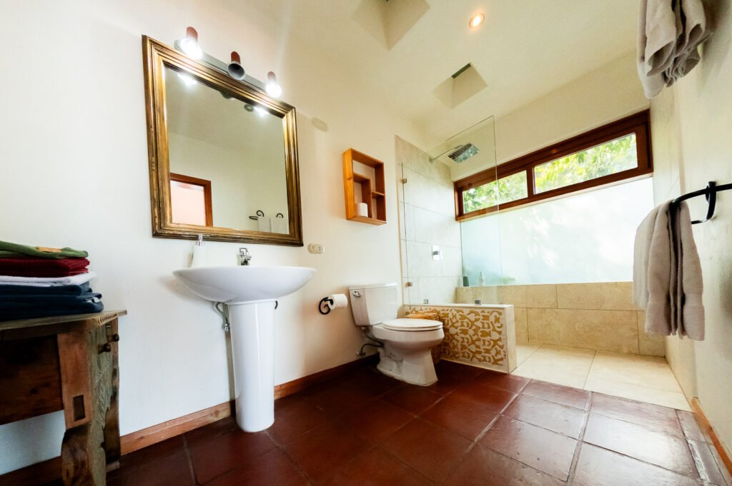 Villa Mirador bathroom with pedestal sink, toilet, and tiled shower area.
