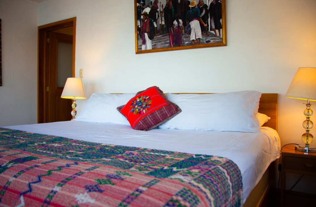 Villa Mirador bedroom with a colorful blanket, decorative pillows, and indigenous artwork above the bed.