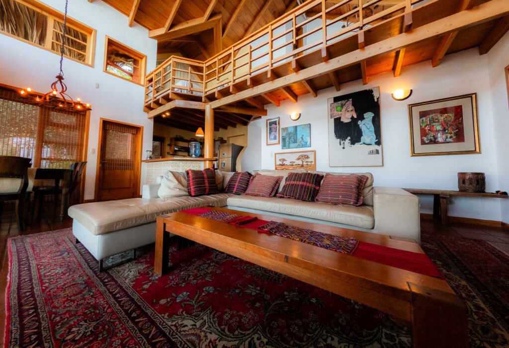 Villa Mirador living room with a large sectional sofa, wooden beams, and a red patterned rug.