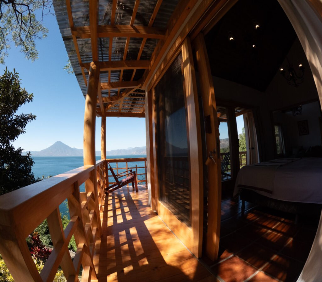 Villa Shakti balcony view of Lake Atitlan, Guatemala, with a chair and open sliding doors.
