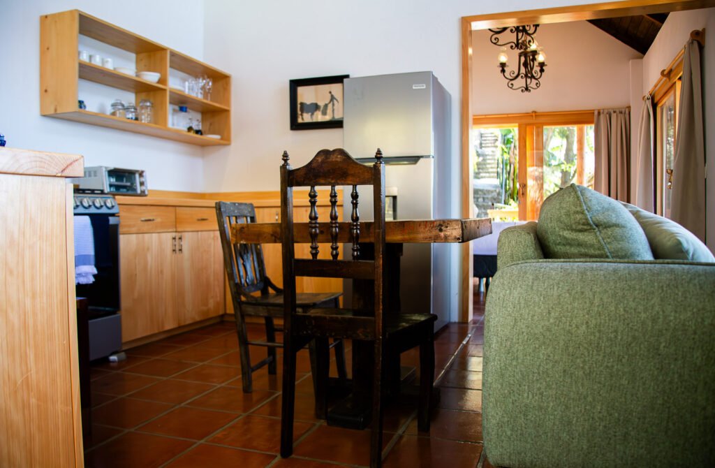 Villa Shakti kitchen with terracotta tile floor, wooden table and chairs, and stainless steel refrigerator.