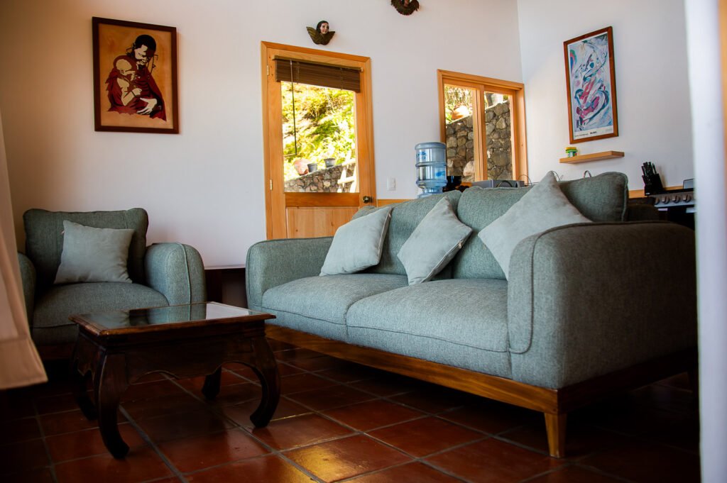 Villa Shakti living room with gray sofa, armchair, and terracotta tile floor.