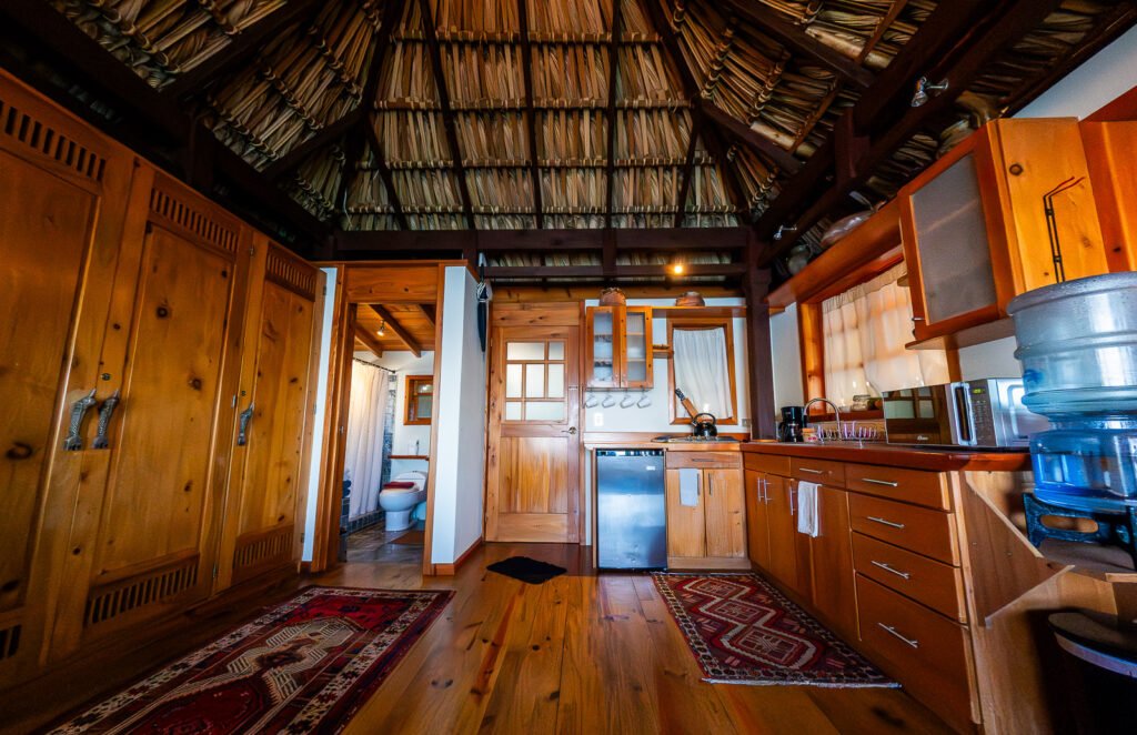 Villa Soluna kitchen interior with wooden cabinets, thatched roof, and bathroom view.