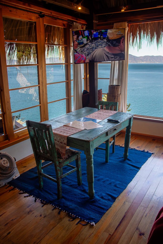 Villa Soluna dining area with lake view, rustic table, and TV. Cozy interior.